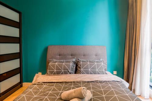 a bedroom with a bed with a blue wall at H20 Residence Ara Damansara by Airhost in Petaling Jaya