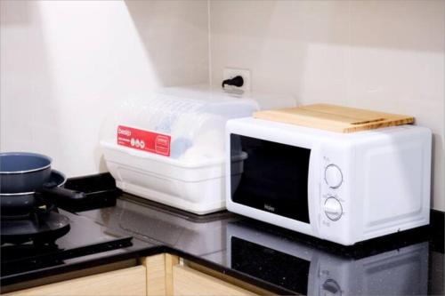 a white microwave sitting on top of a kitchen counter at Spacious 4BRTownhouse BTS Onnut 10 Sleeps with Parking in Amphoe Phra Khanong