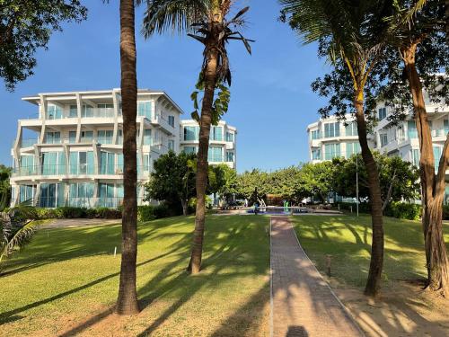 a building with palm trees in front of it at Luxury Penthouse, Nilaveli in Trincomalee