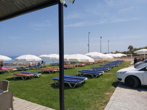a row of lounge chairs and umbrellas on the beach at Hotel Pia Bella in Kérynia