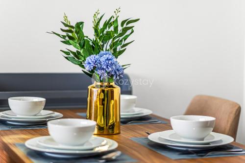 a table with a yellow vase with blue flowers in it at Vista by Kozystay - Alam Sutera in South Tangerang