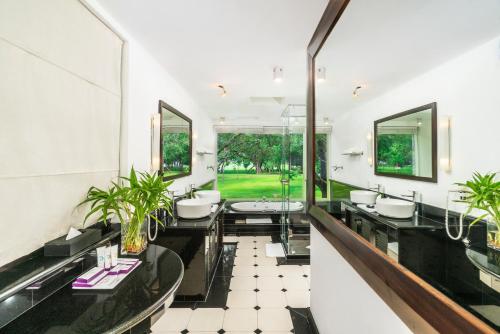 a bathroom with four sinks and two mirrors at Cinnamon Lodge Habarana in Sigiriya