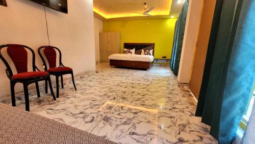 a room with a bed and two chairs and a marble floor at Hotel MountMemory , Barkot-Yamunotri in Barkot