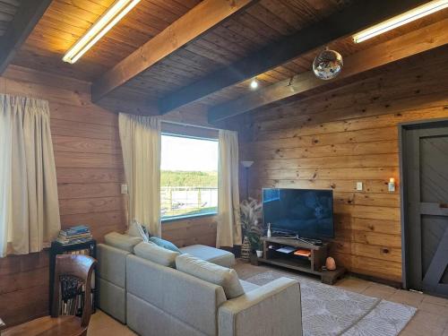 a living room with a couch and a flat screen tv at Equestrian Farm Stay in Tahorakuri