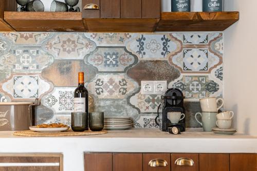 a kitchen with a tile wall with a bottle of wine at Yria Traditional House in Vívlos