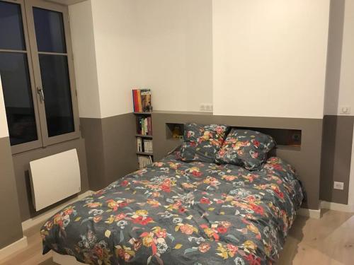 une chambre avec un lit avec une couette fleurie dans l'établissement Au coeur de Versailles, à Versailles