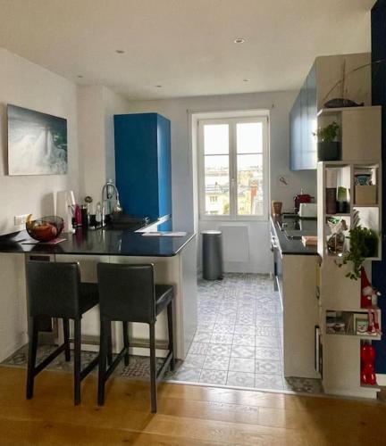 une cuisine avec des armoires bleues et une table et des chaises dans l'établissement Au coeur de Versailles, à Versailles