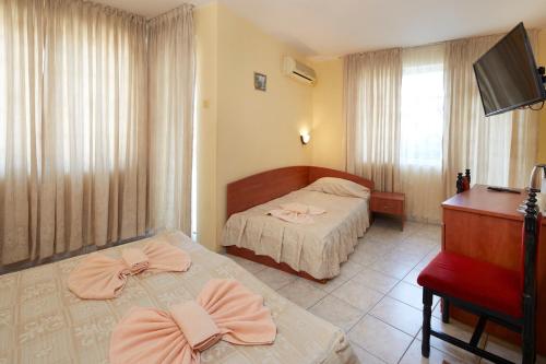 a hotel room with two beds and a desk at Family Hotel Andreev in Nesebar