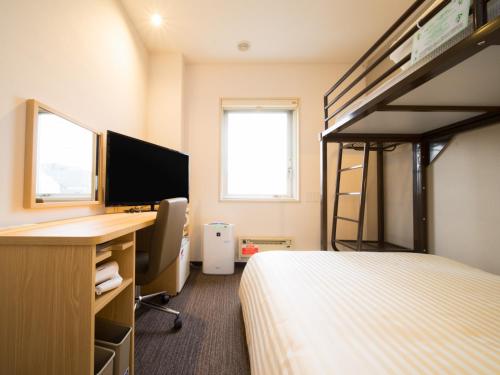 a bedroom with a bunk bed with a desk and a computer at Super Hotel Kitami in Kitami