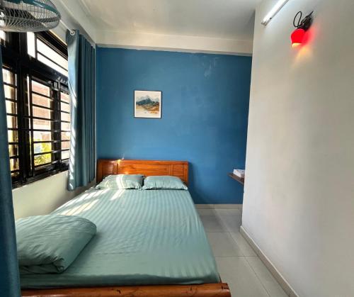 een slaapkamer met een bed met een blauwe muur bij Nhà Nghỉ FAMI in Ho Chi Minh-stad