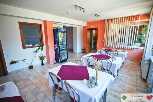 een restaurant met witte tafels en stoelen en oranje muren bij Noroc si Fericire in Târgu-Mureş