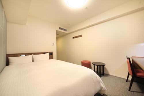 a bedroom with a white bed and a desk at Richmond Hotel Kagoshima Kinseicho in Kagoshima
