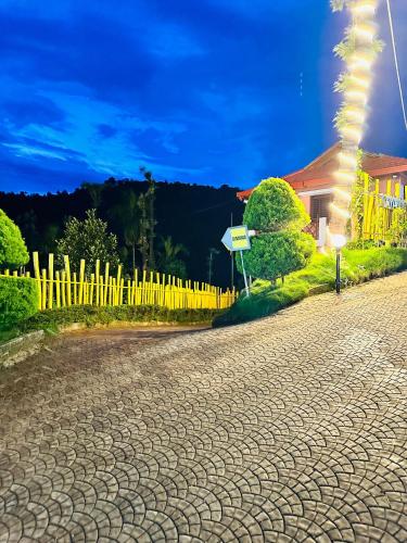 a cobblestone road in front of a yellow fence at Aayana Valley in Chikmagalur