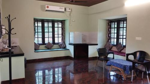 a room with a kitchen and a table and chairs at Panchatattva Homestay in Belmannu
