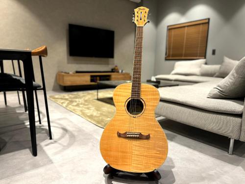 a guitar sitting on a stand in a living room at TABISAI HOTEL Lunon Tenjin in Fukuoka