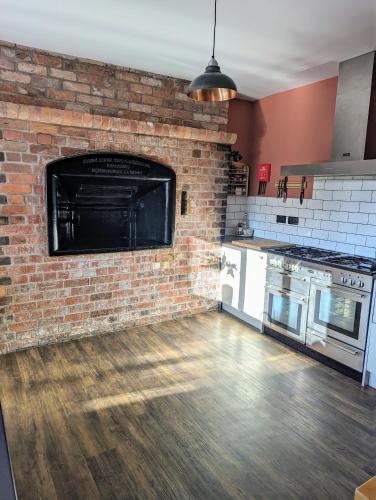 a kitchen with a brick wall and a hard wood floor at The Cob House. in Ifton Heath