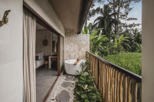 a bathroom with a bath tub on a balcony at Suara Alam Hotel Ubud by Ini Vie Hospitality in Ubud
