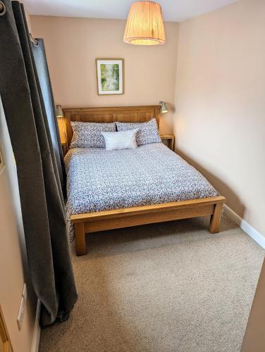 a bedroom with a wooden bed with a lamp at The Cob House. in Ifton Heath