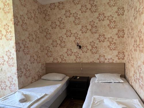 two twin beds in a room with wallpaper at Nina two in K'obulet'i