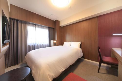 a bedroom with a bed and a desk and a window at Richmond Hotel Kagoshima Kinseicho in Kagoshima