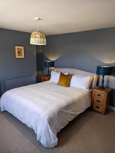 a bedroom with a large white bed with blue walls at The Cob House. in Ifton Heath
