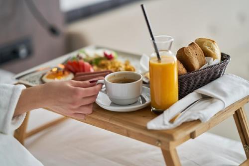 a person holding a cup of coffee and a tray of food at Navita Cave Houses in Fira
