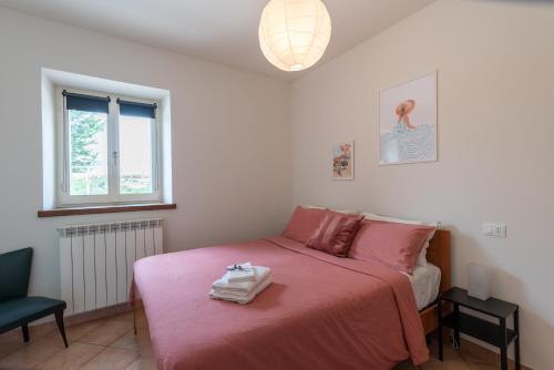 a bedroom with a pink bed and a chair at L'Antica Colombaia Appartamenti in Ostra