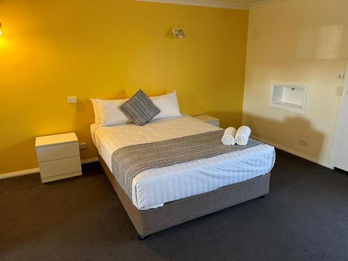 a bedroom with a bed with two shoes on it at Mid City Plantation Motel in Mildura