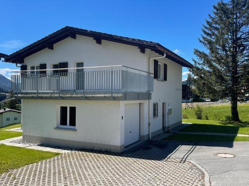 a white house with a balcony and a driveway at Ski in Ski out Family accommodation Chesa Katja Lenzerheide in Valbella