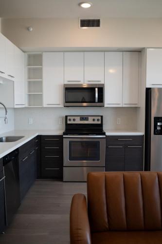 a kitchen with stainless steel appliances and white cabinets at 5 Min from everything! Pool, Gym, Balcony in Houston