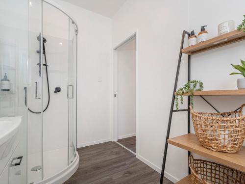 a bathroom with a shower and a sink at Valley Hideaway - Kūaotunu Holiday Cabin in Kuaotunu