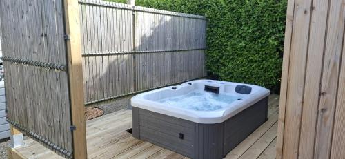 un bain à remous installé sur une terrasse à côté d'une clôture dans l'établissement Location Finistère Jaccuzi privé, à Plougourvest