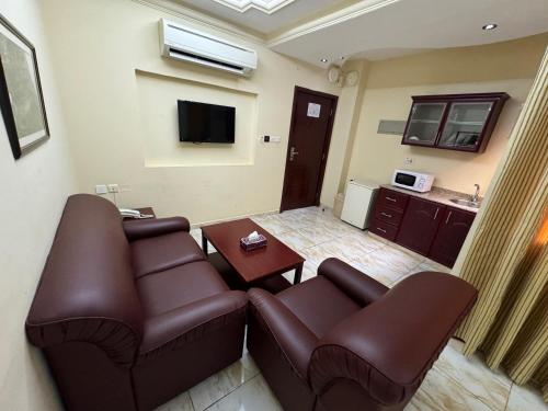 a living room with two leather couches and a tv at Al Ferdous Hotel Apartments in Muscat