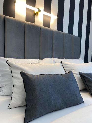 a bed with white pillows and a gray headboard at Studio Luxury Black & White in Alba Iulia