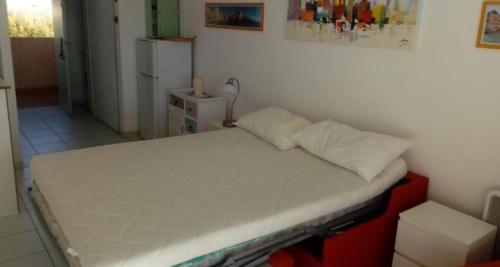 - un petit lit dans une chambre dotée d'un mur blanc dans l'établissement Studio Cala Sognu Moriani residence, à San-Nicolao