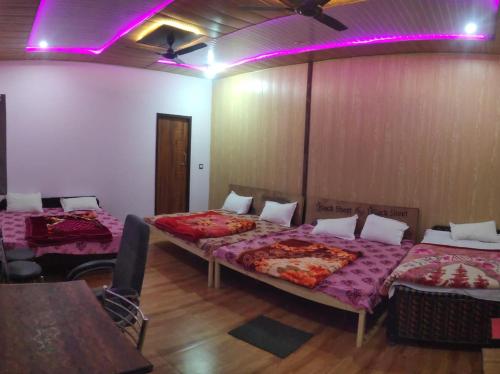 a room with two beds with purple lights on it at Hotel Trishul Inn in Karnaprayāg