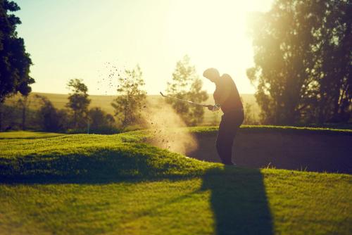 a man hitting a golf ball with a club at Hotel Erbprinz - Gourmet & Spa in Ettlingen