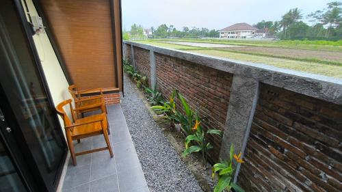 a porch with two chairs and a brick wall at Harmony Magelang Syariah in Bendo