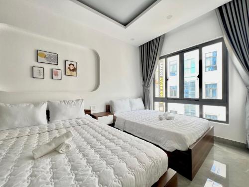 a bedroom with two beds and a large window at Cassie Boutique Hotel in Vung Tau