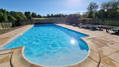 a swimming pool in a backyard with picnic tables at Domaine du Raysse in Saint-Cirq