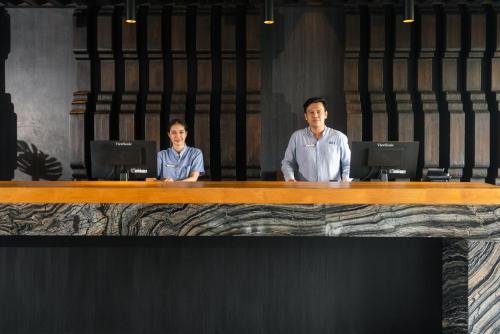 a man and woman sitting at a desk with laptops at Hotel IKON Phuket - SHA Extra Plus in Karon Beach