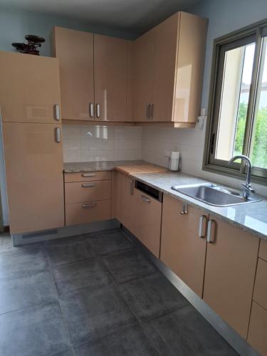 une cuisine avec des armoires en bois, un évier et une fenêtre dans l'établissement La gloriette, à Saumane-de-Vaucluse