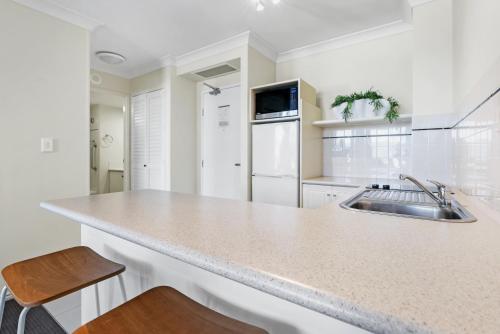 a white kitchen with a sink and a counter at Esplanade Escape in Cairns