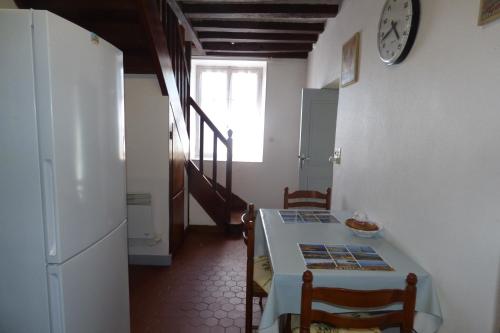 une cuisine avec une table, des chaises et une horloge murale dans l'établissement campagnarde, à Quettetot