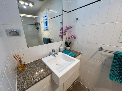 un bagno bianco con lavandino e specchio di 2BR Apt Gungahlin Square Luxe Super Central Wifi Wine Secure Parking a Canberra