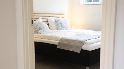 a bedroom with a bed with white sheets and pillows at Møllehusets lejligheder i Ikast tæt ved Herning, Silkeborg og Århus in Ikast