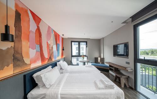 a bedroom with two beds and a large painting on the wall at TK Phu Quoc Hotel - Grand World Phu Quoc in Phu Quoc