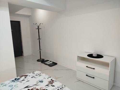 une chambre blanche avec un lit et une commode dans l'établissement Studio Tudor Eforie Nord, à Eforie Nord
