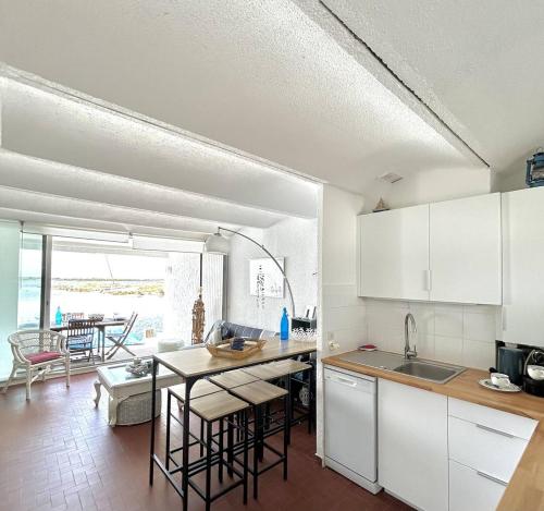 une cuisine avec des armoires blanches et une table avec des chaises dans l'établissement Charmant triplex au bord de l'eau 5VDB29, au Barcarès