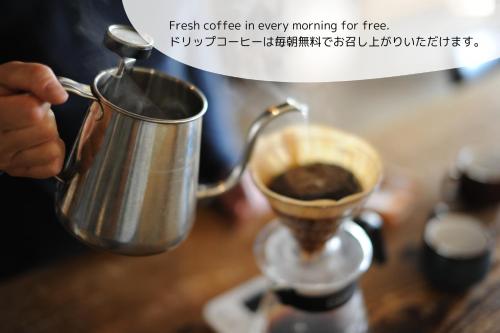 a person holding a coffee pot on a table at 1166 Backpackers in Nagano